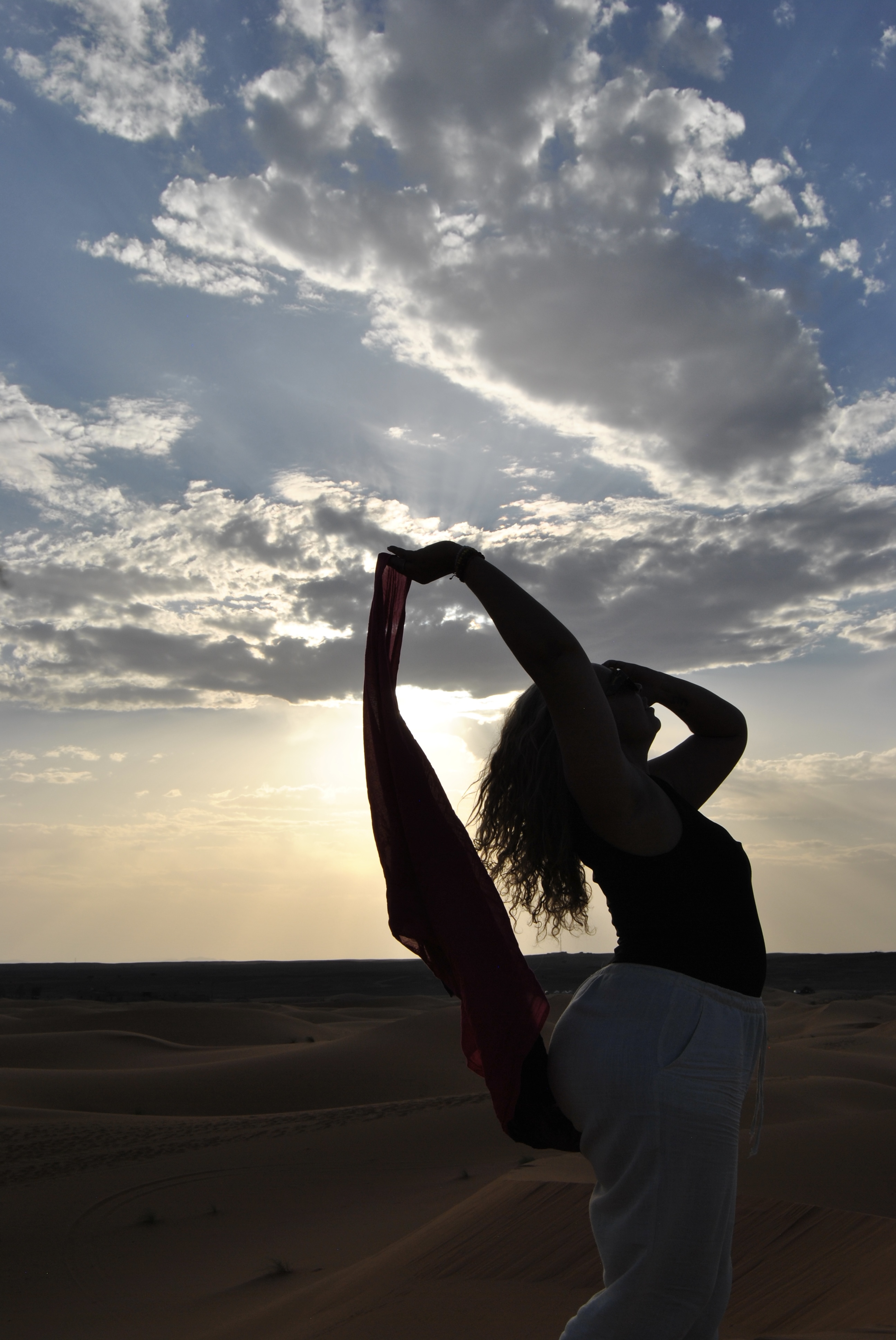 Mujer con velo al viento en las dunas del desierto al atardecer